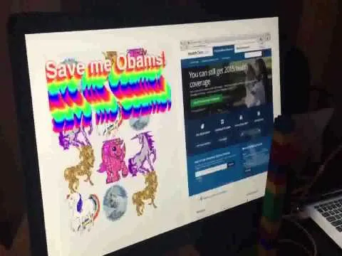 Video: a monitor showing a healthcare.gov rebuild covered in rainbow "Save me Obama!" lettering and glittering unicorns